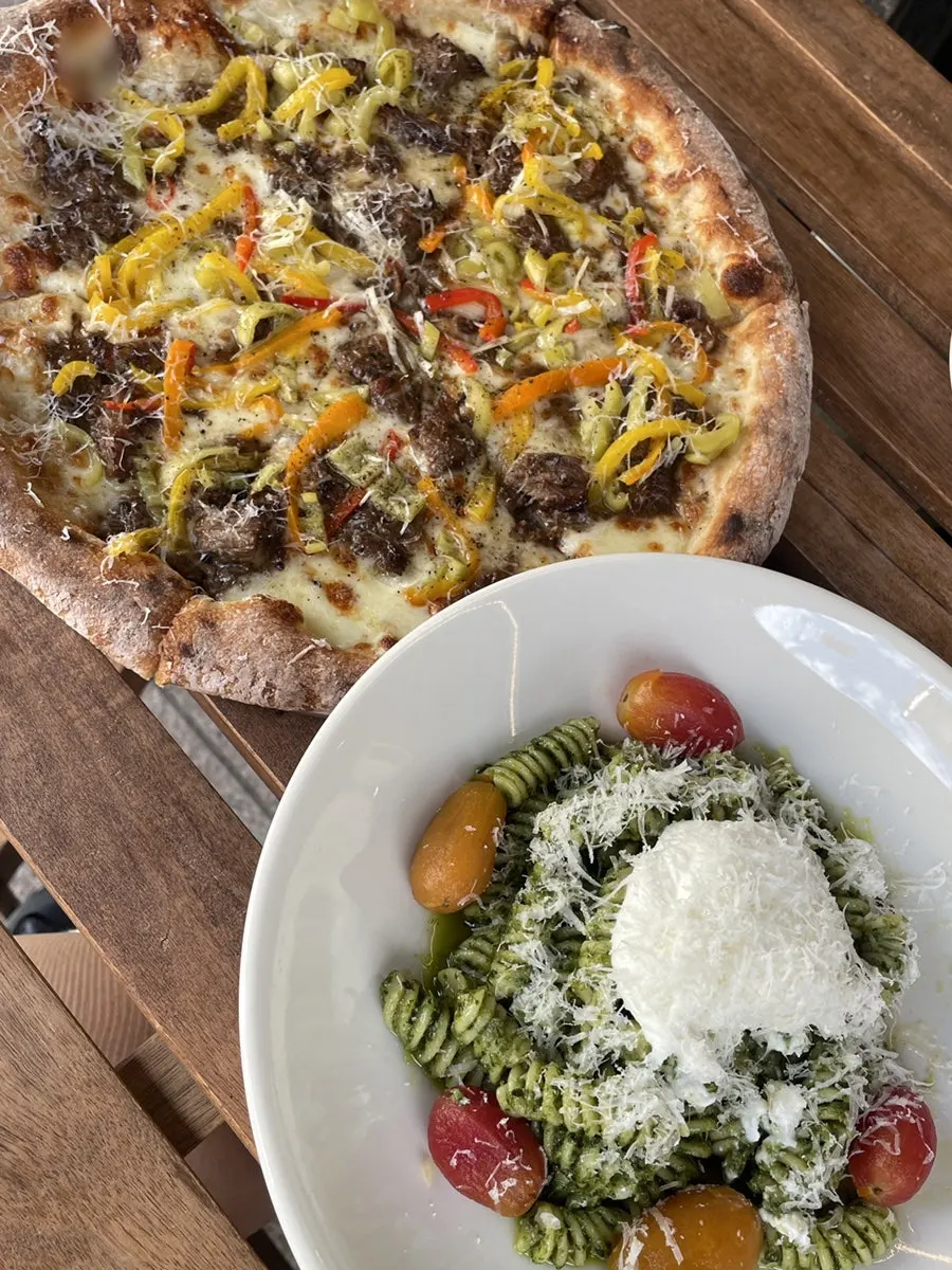 Pizza, pasta, and non-alcoholic beer set on the terrace table