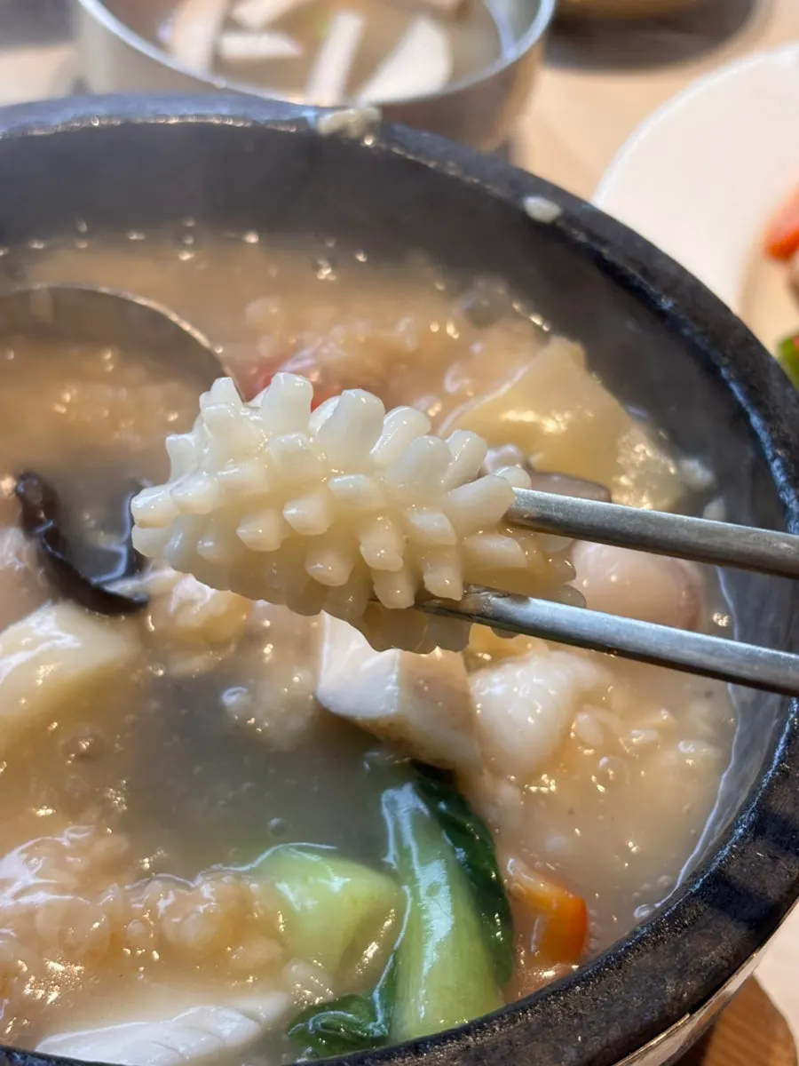 Enjoying the seafood nurungjitang earthenware pot mid-meal