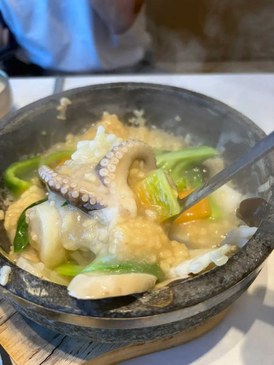 A bite of scorched-rice soup topped with seafood and vegetables