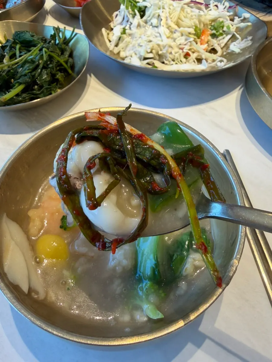 A bite of scorched-rice soup wrapped with green onion kimchi