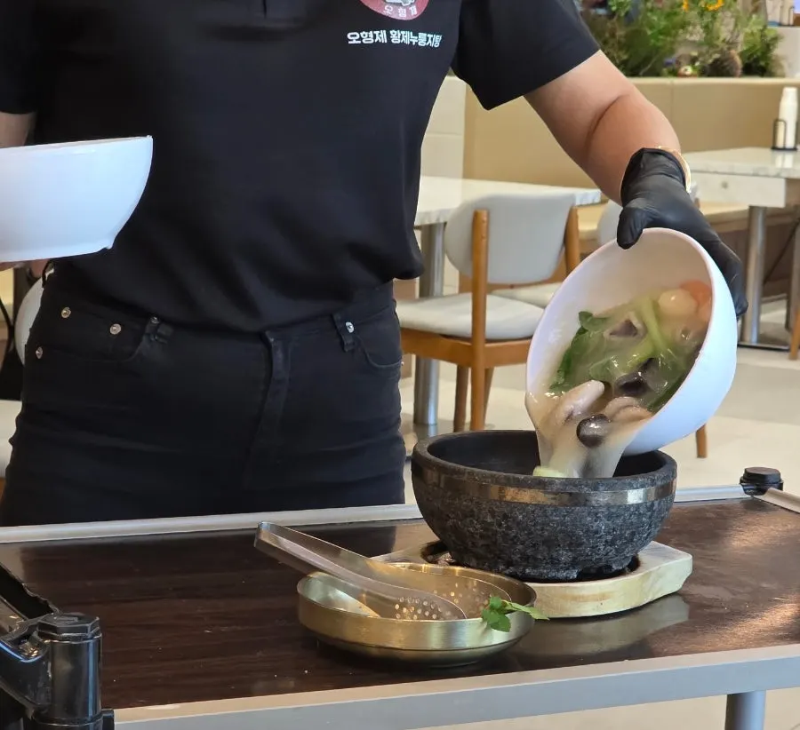 Broth and scorched rice being poured into the stone pot tableside