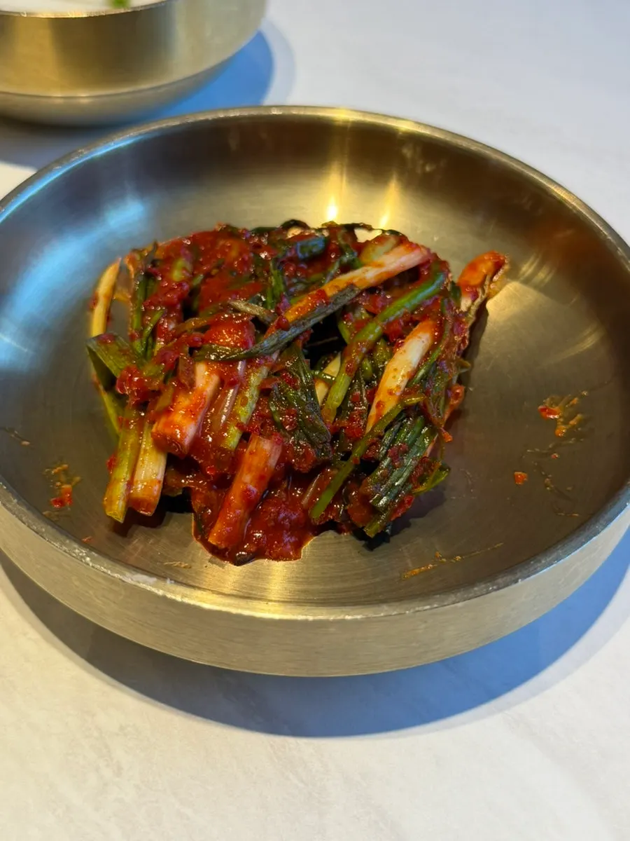 Bowls of squid radish strips and green onion kimchi among the side dishes