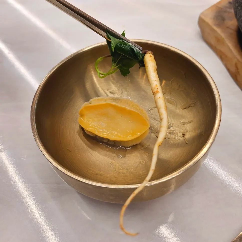 Nurungjitang topped with abalone and young ginseng sprouts