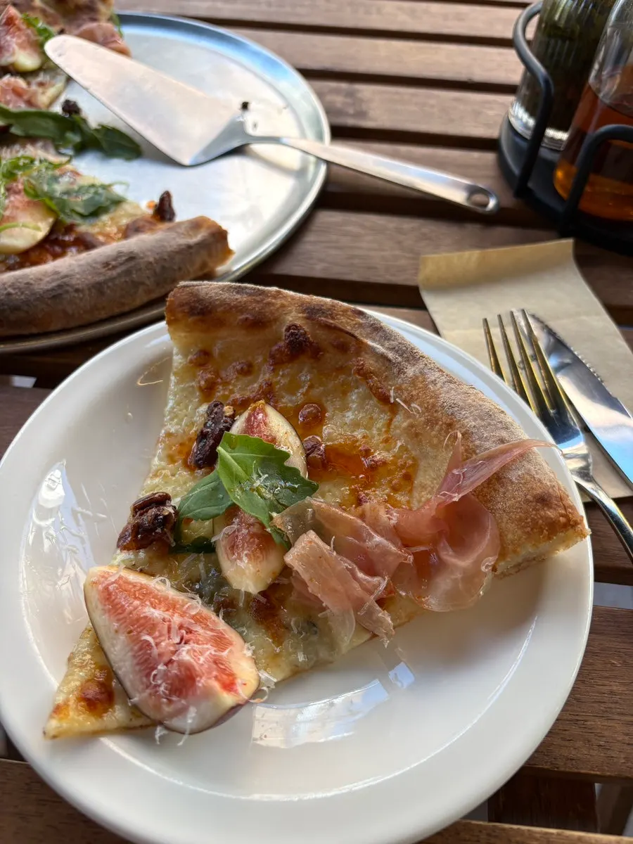 Cross-section of pizza piled high with prosciutto