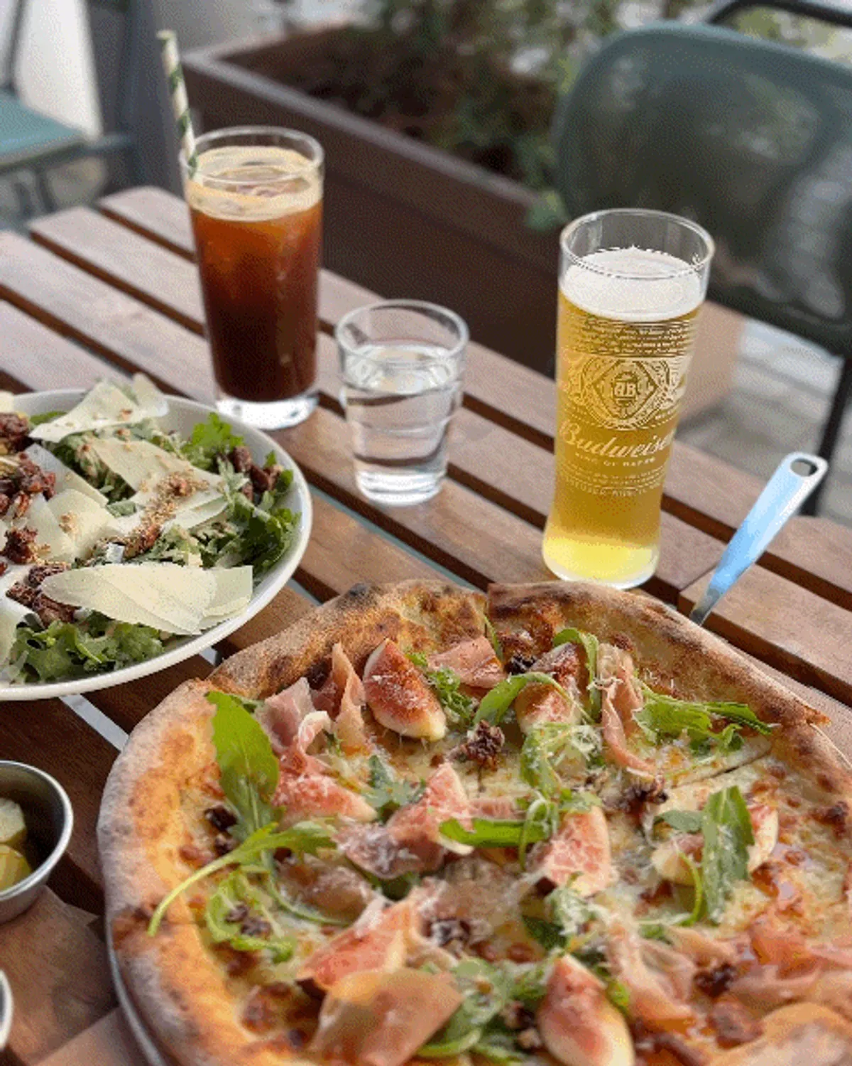 Pizza and draft beer spread on the terrace table
