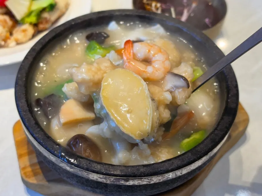 Seafood abalone rice soup ladled into a bowl