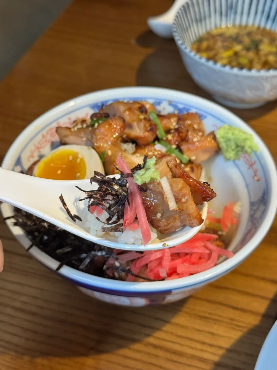 A bite of yakitori don with seaweed flakes and ginger