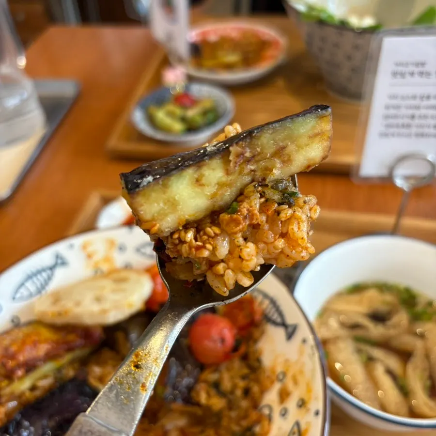 A spoonful of the rice bowl with eggplant tempura