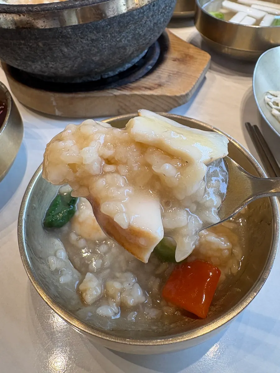 A spoonful combining seafood, broth, and nurungji