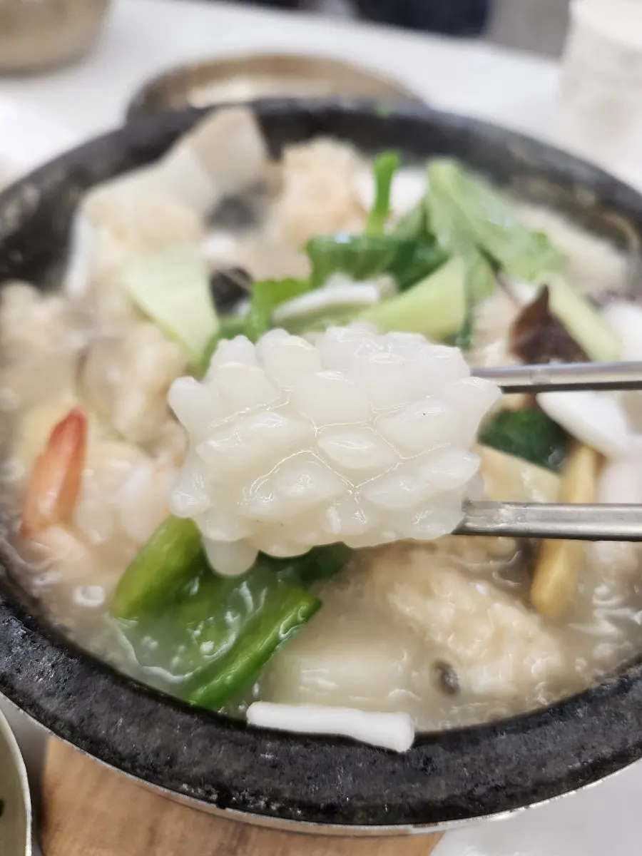 Individual hot stone pot seafood abalone nurungjitang topped with saessak-sam and abalone