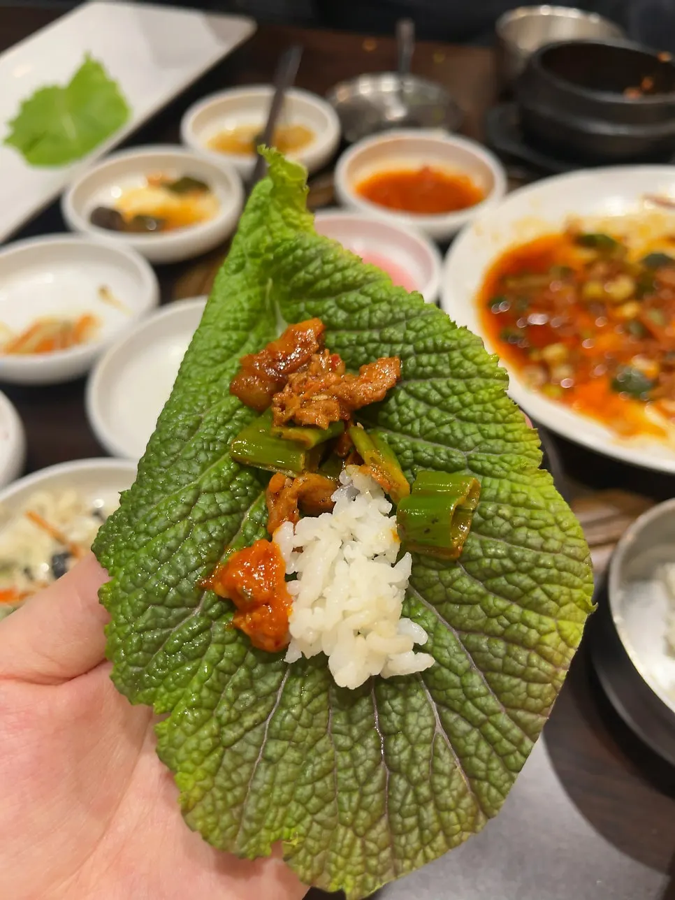 쌈채소 한 장을 집어 든 모습