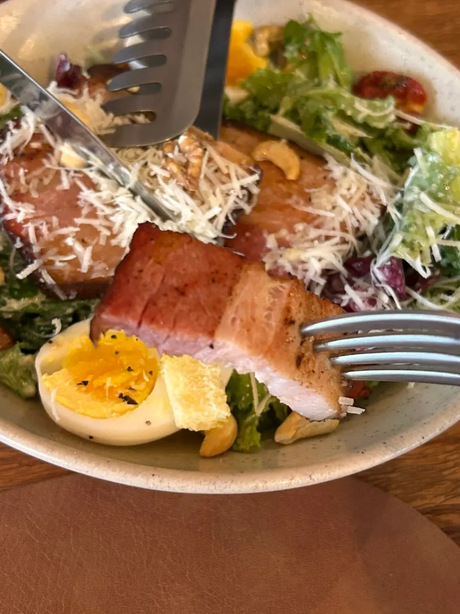 Cross-section of homemade bacon on the Caesar salad