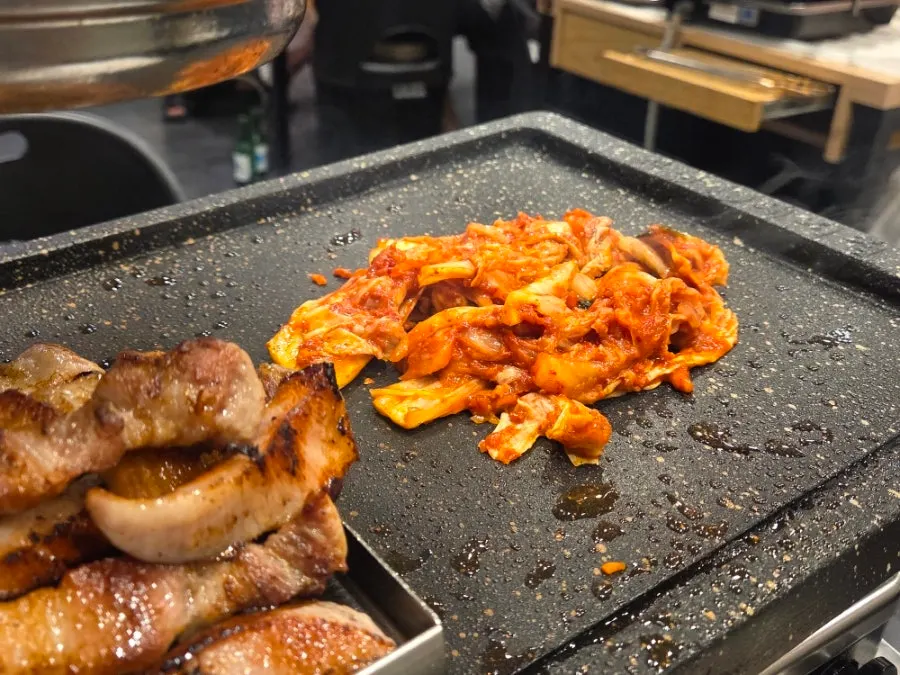 Grilled meat placed on a metal plate atop the stone griddle