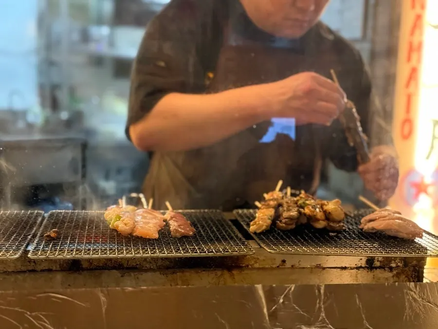 Staff's hands carefully grilling one skewer at a time