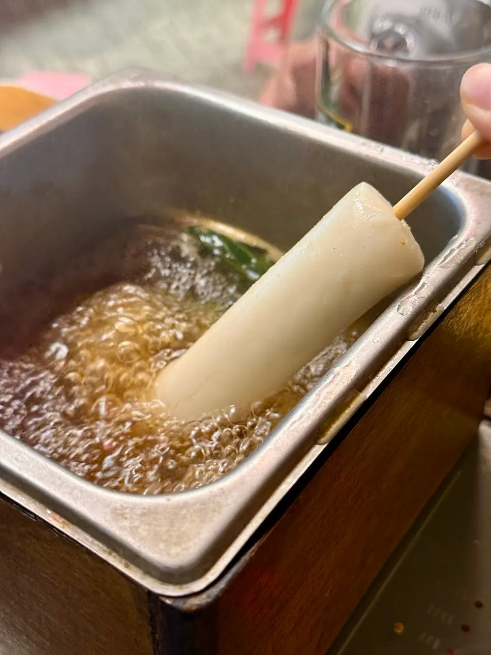 Three skewers of oden served in a pot with broth