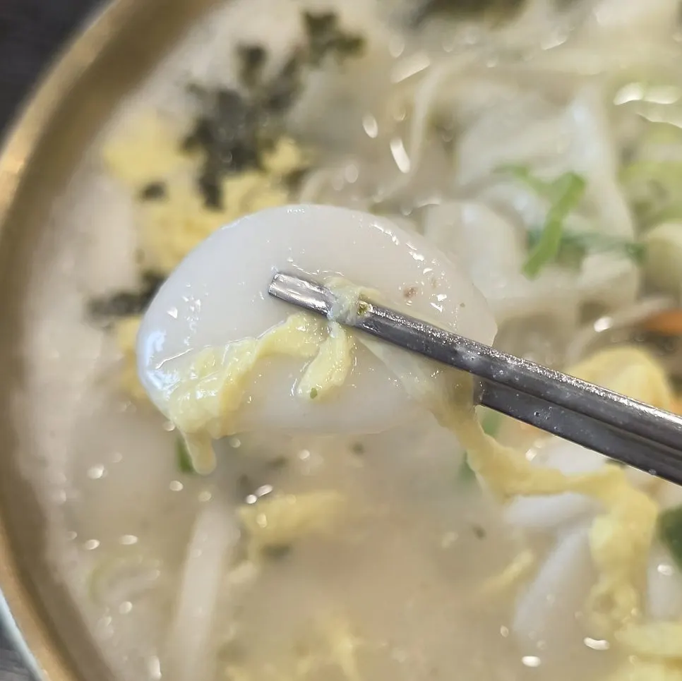 Close-up of tteokguk seolleongtang broth and chewy rice cakes