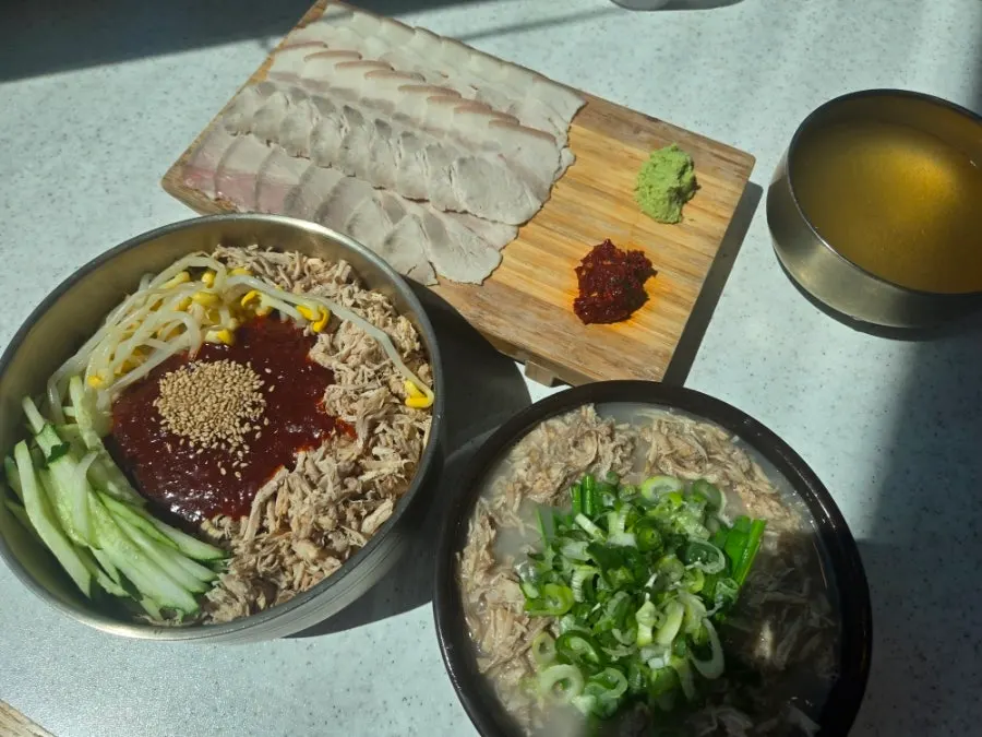 Table set with lean pork rice soup, dongchimi bibim noodles, and dombe naengsuyuk
