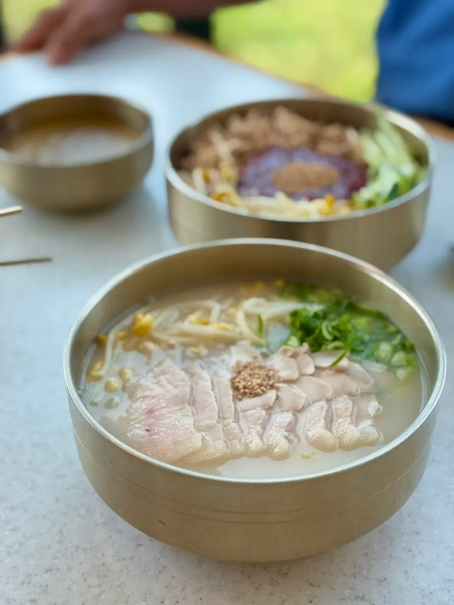 A bowl of bone-broth pork noodle soup topped with Jeju pork