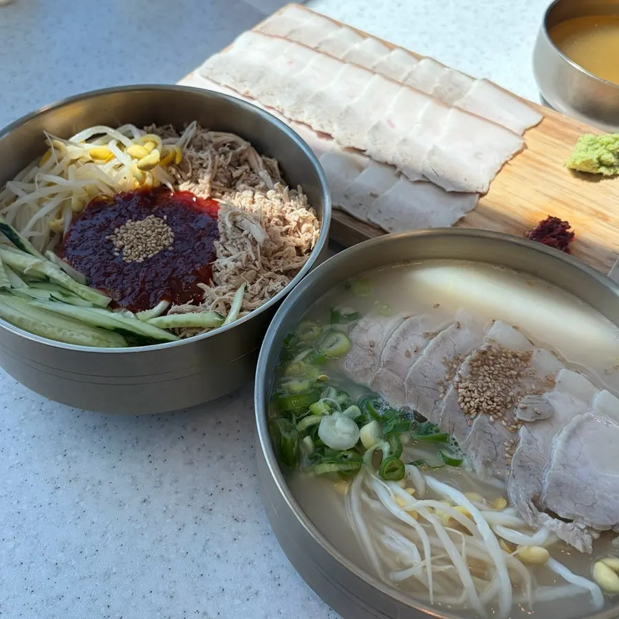 Table setting with dongchimi bibim noodles and bone-broth pork noodle soup