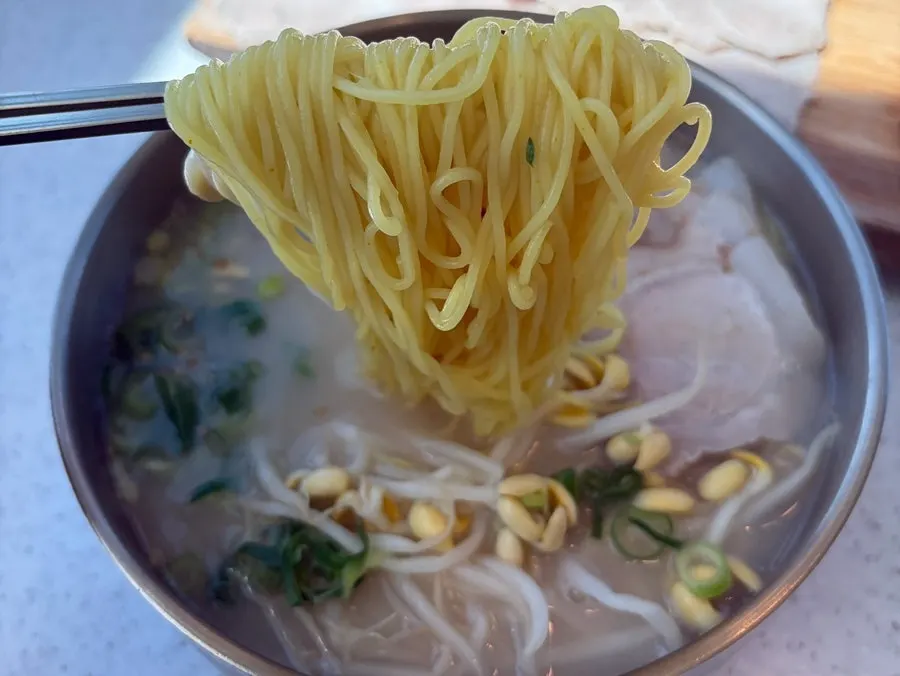 Chopsticks lifting up chewy noodle strands