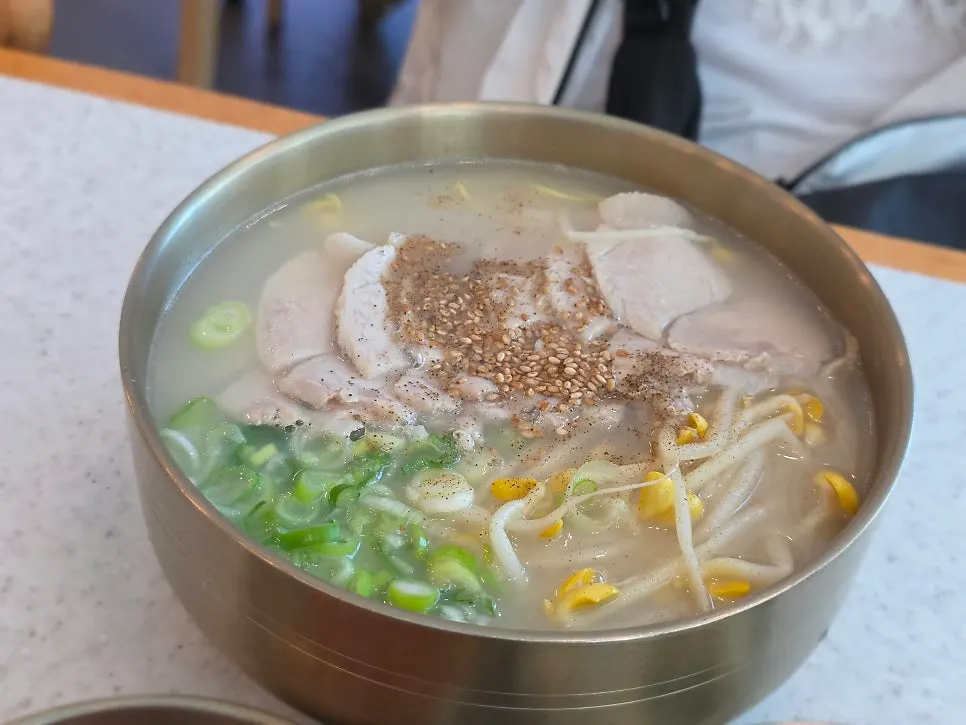 A bowl of bone-broth pork noodle soup topped with garnish