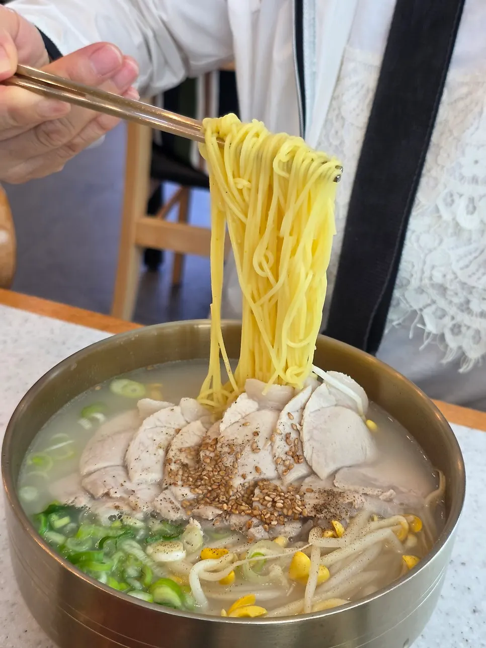 Noodles lifted up with chopsticks from the pork noodle soup