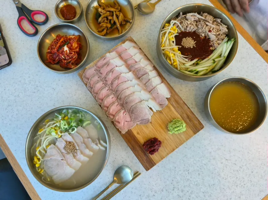 창가 테이블에 차려진 국수 두 그릇과 수육