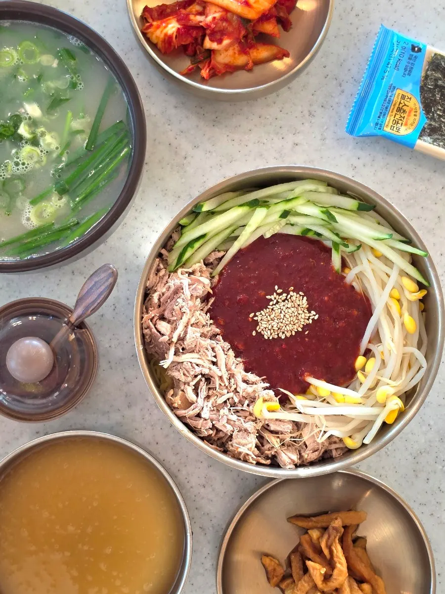 Chopsticks lifting a strand of dongchimi bibim noodles