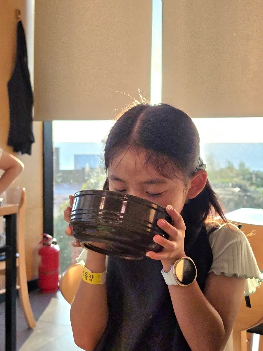 A child in a baby chair drinking the rice soup broth