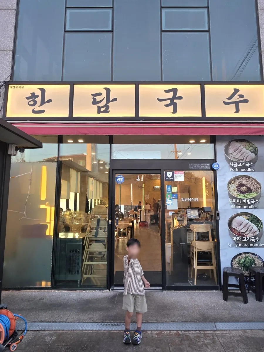 A child giving a thumbs up in front of Handam Guksu Gwakji Aewol Branch