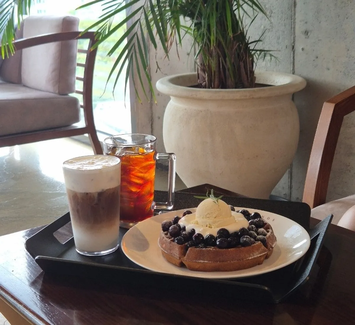 Table with blueberry cream cheese waffle and two cups of coffee