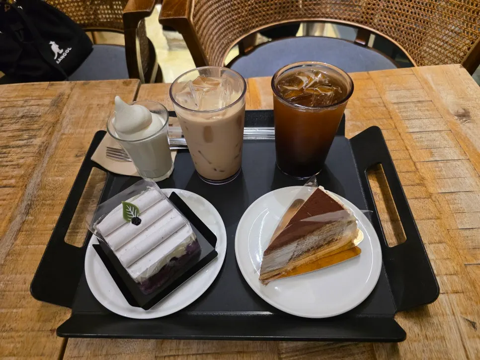 Drinks and cakes served together on a black tray