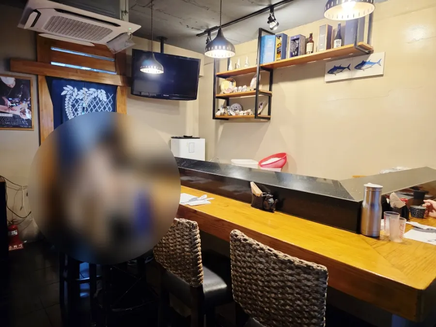 Wood-toned interior of Hangil Tuna with counter seating under warm lighting