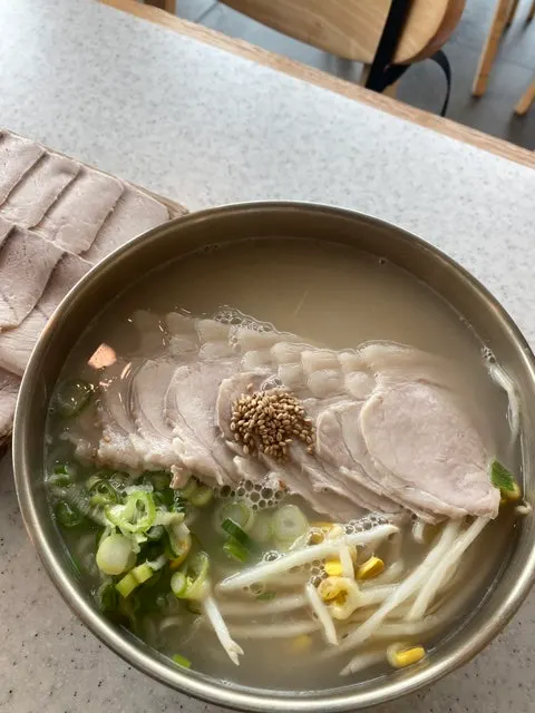 Lifting up noodles and broth from the pork noodle bowl