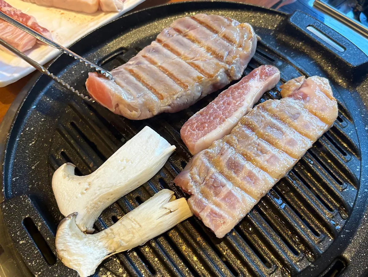 Pork belly grilling on a uniquely shaped grill plate