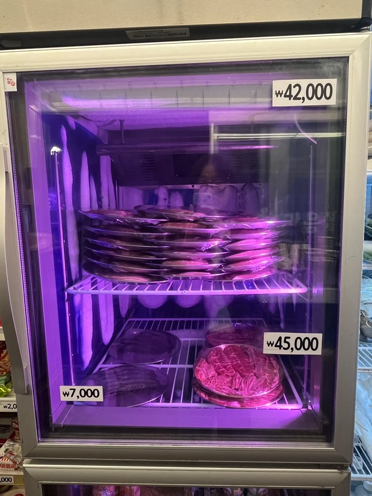 Meat display case with pork and beef tray prices posted