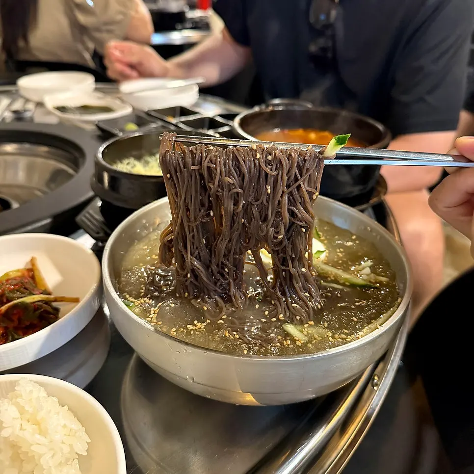 Lifting up a bite of the naengmyeon noodles