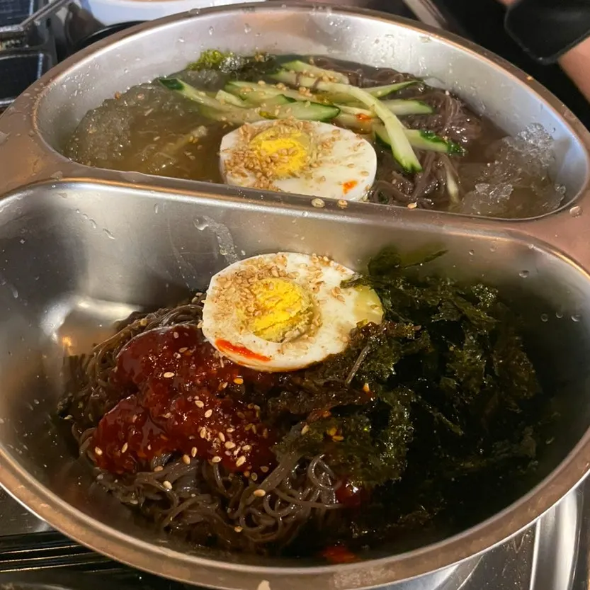 Bowl of half-and-half naengmyeon with eggs on each side