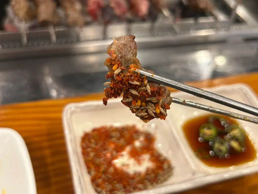 A beer glass set next to lamb skewers