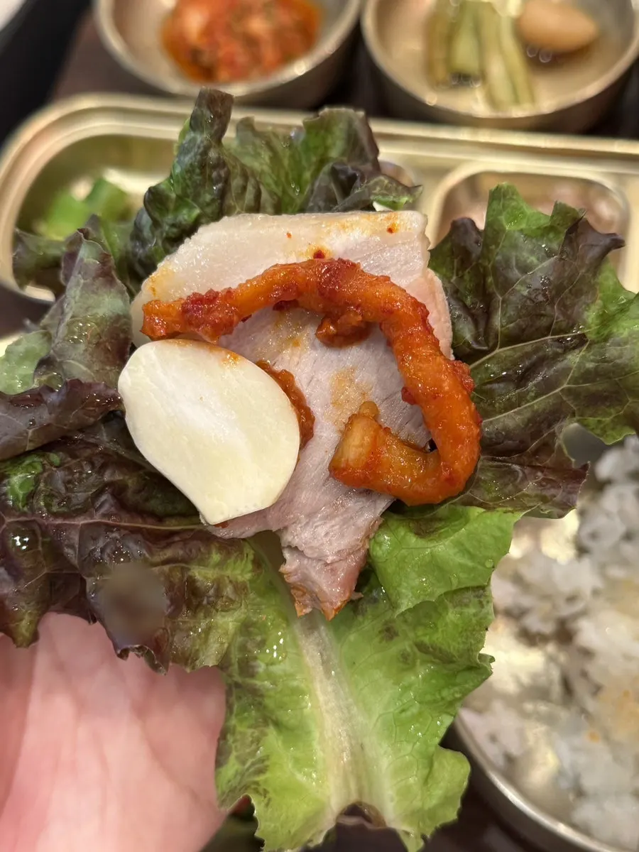 무김치를 올린 보쌈 한 점