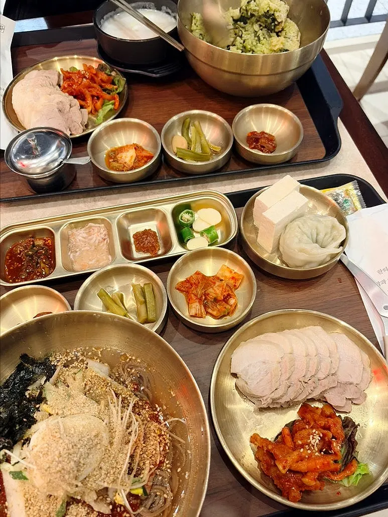 Table with the bibim makguksu set, gondre bibimbap and bossam