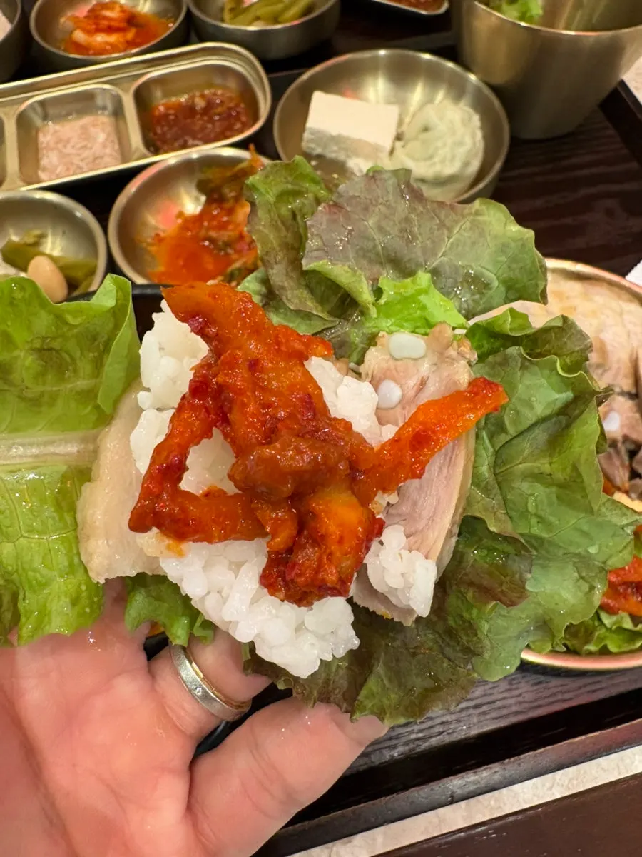 Bossam wrap topped with radish kimchi and garlic