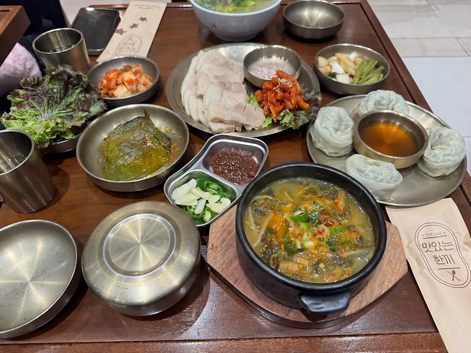 Table with bossam, side dishes, gukbap, and Andong guksu together