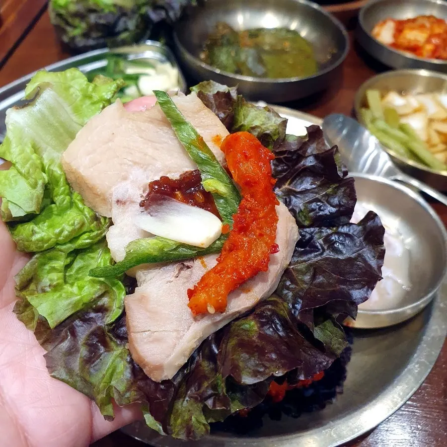 エゴマの葉の漬物と一緒に食べるポッサムの一切れ