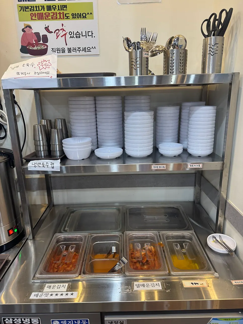 Self-bar corner with warm naengmyeon broth and chili peppers