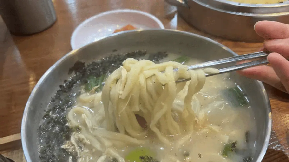 Lifting up the house-made noodles from the dak kalguksu