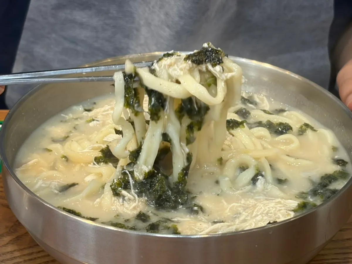 진한 닭육수 칼국수 면을 들어 올린 모습