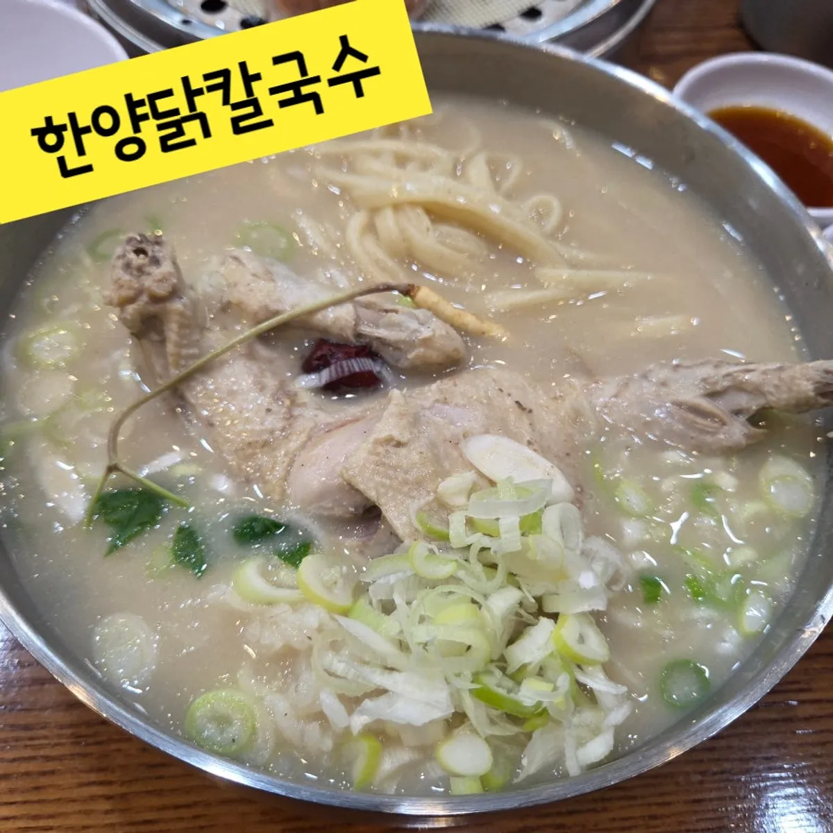 A bowl of samgyetang kalguksu topped with half a chicken
