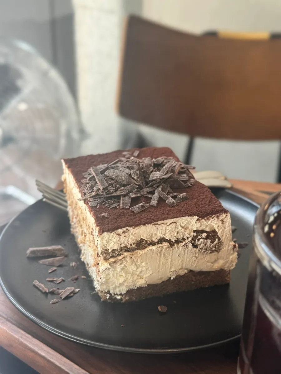 A slice of tiramisu topped with dark chocolate