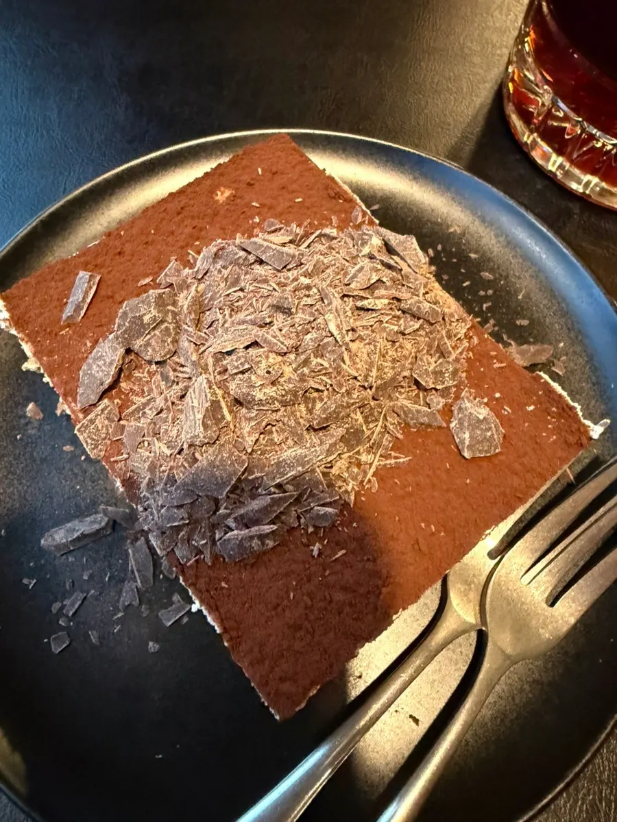 A slice of tiramisu topped with dark chocolate